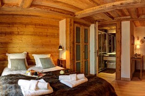 Una habitación acogedora de madera con una cama, una mesita de noche y un baño visible a través de una puerta abierta.
