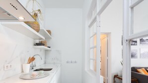 Una cocina moderna con armarios blancos, encimera negra y ventana con vistas a un paisaje urbano.
