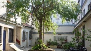 A narrow alley with a tree, a bike rack, and buildings on either side. - Paris 20 Pere Lachaise: VERY QUIET STUDIO WITH A TERRACE (Paris)