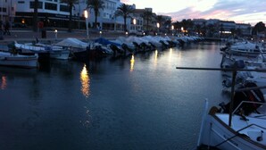 A marina with boats docked, a waterfront restaurant, and palm trees along the shore.