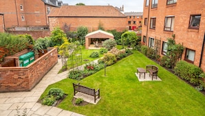 A courtyard with a lawn, a wooden bench, and a covered seating area. - York City Centre Luxurious Apartment with FREE ONSITE PARKING! (York)