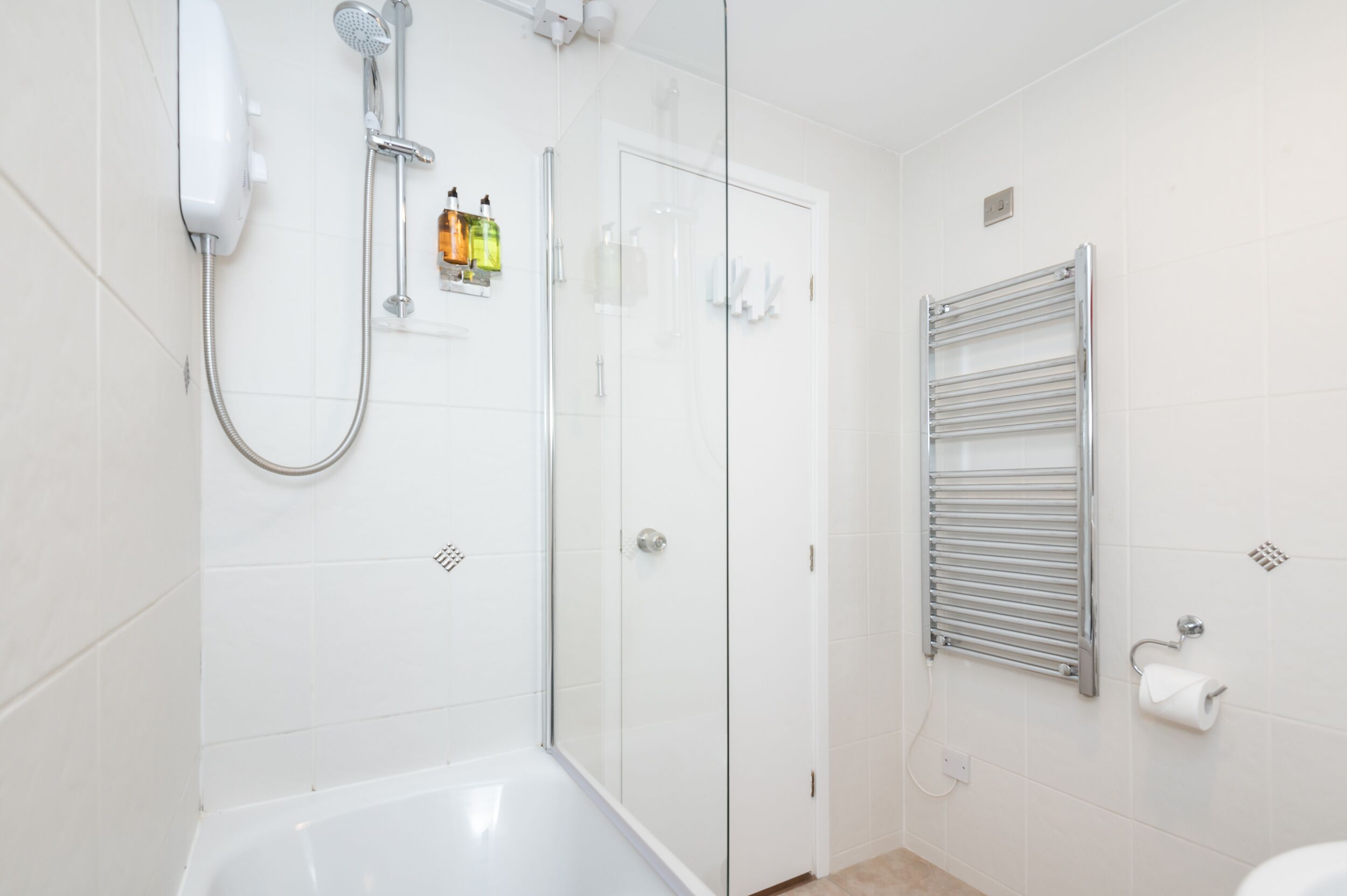 Une salle de bain moderne dotée d’une douche à parois de verre, de toilettes intégrées et d’un porte-serviettes.