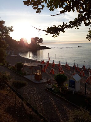 A beachside area with a stone pathway, a small wooden shelter, and orange lifeguard stands.