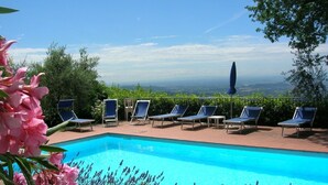 Une piscine à l’eau d’un bleu cristallin, entourée de chaises longues et offrant une vue sur le paysage.