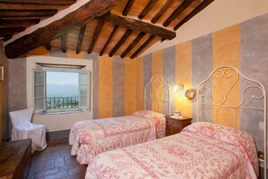 Una camera da letto con due letti, una finestra vista e un soffitto in legno.