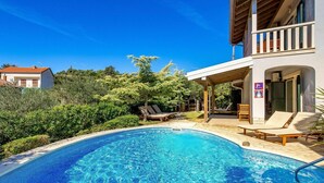 Une piscine avec des chaises longues et un espace patio couvert.