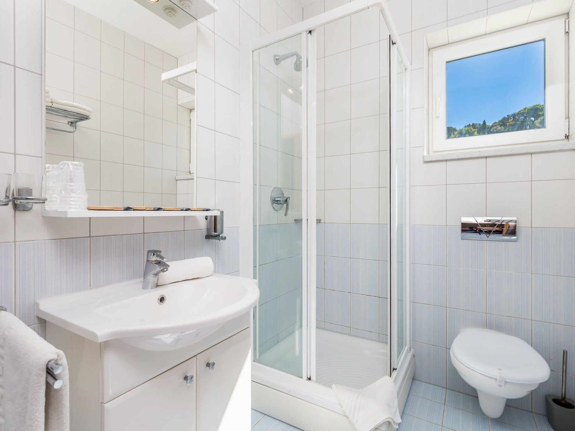 Un baño moderno con ducha acristalada, lavabo blanco y retrete.