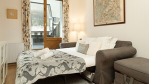 A bedroom with a bed, a sofa, a lamp, a map on the wall, and a window with curtains.