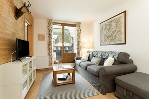 Un salon avec un téléviseur, un canapé, une table basse et une carte accrochée au mur.