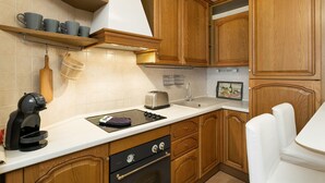 A kitchen with wooden cabinets, a white countertop, a toaster, a coffee maker, and a sink.