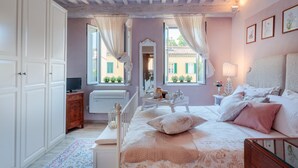 A bedroom with a bed, bedside table, dresser, and a window with curtains. - Convenient Home close to Train Station and Parking (Lucca)