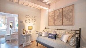A cozy bedroom with a bed, a bedside table with a lamp, and a wall adorned with framed maps. - Convenient Home close to Train Station and Parking (Lucca)