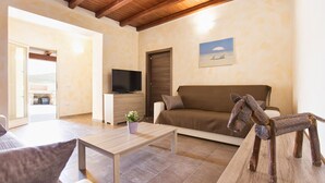 Una sala de estar con un sofá, una mesa de centro, un televisor y una silla de madera.