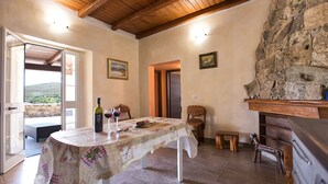 Un comedor con una mesa dispuesta para dos, una chimenea de piedra y vistas al exterior.