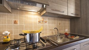 Una cocina moderna con estufa a gas, pileta de acero inoxidable y muebles de madera.