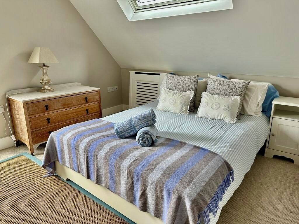 A bedroom with a bed, bedside tables, a lamp, and a window.