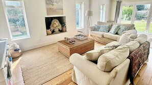 Un salon spacieux avec un grand canapé, une cheminée et une vue sur le jardin.