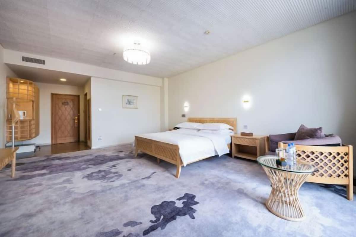 A bedroom with a bed, bedside table, and a seating area with a chair and table.