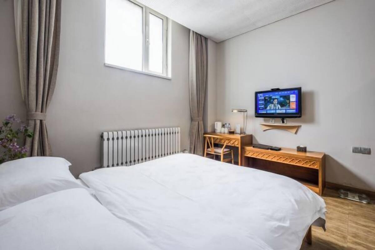 A hotel room with a bed, a desk, a television, and a window.