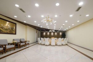 Un salón de conferencias con una mesa redonda, sillas y un candelabro.