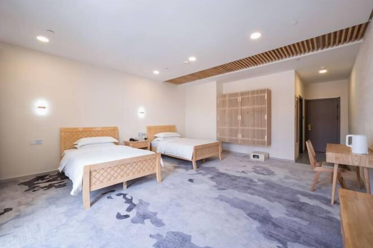 A hotel room with two beds, a dining table, and a small kitchenette.