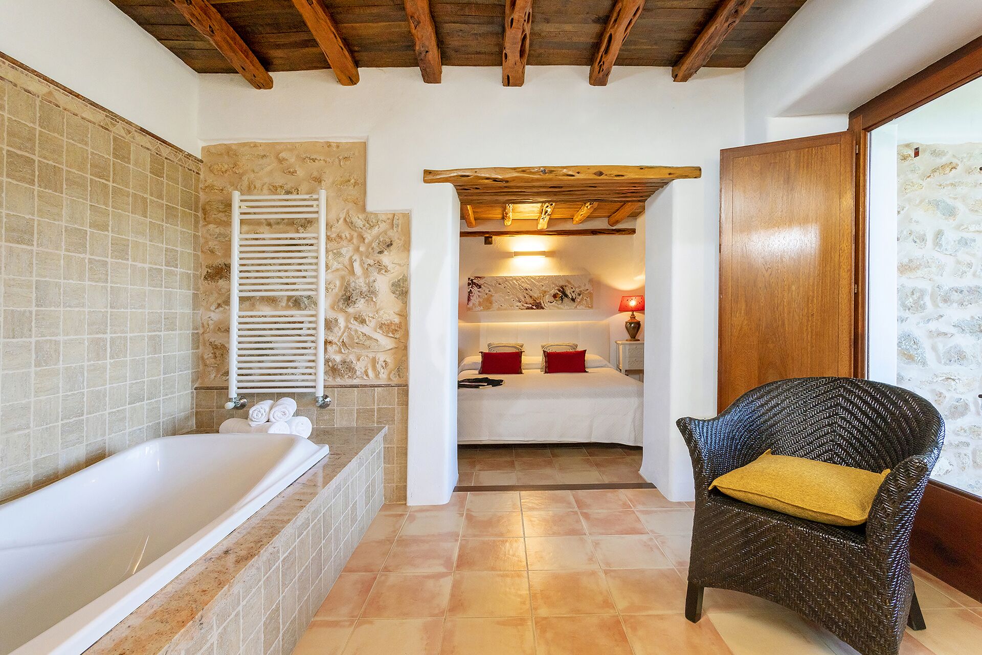 Un baño con bañera, perchero y una silla de mimbre con cojín.