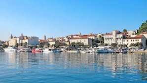 Une ville côtière dotée de bâtiments historiques, d’un port de plaisance où sont amarrés des bateaux et d’un ciel d’un bleu limpide.