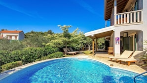 Une piscine avec des chaises longues et un espace patio couvert.