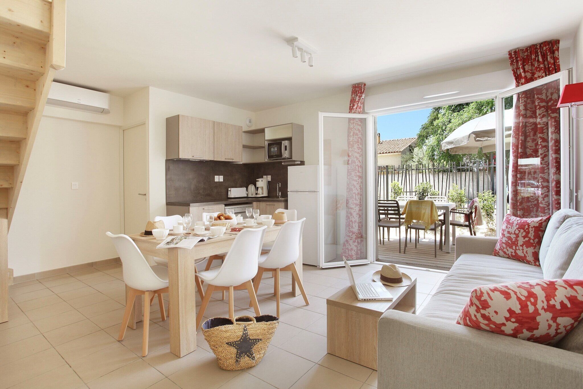 A modern apartment with a dining area, kitchen, and a living room with a sofa and a table.