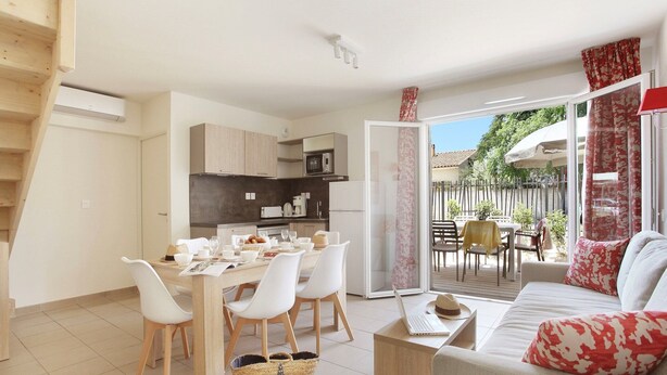 Un apartamento moderno con comedor, cocina y sala de estar con sofá y mesa.