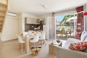 A modern apartment with a dining area, kitchen, and a living room with a sofa and a table.