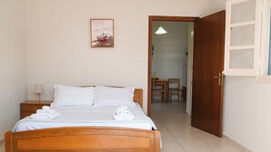A neatly made bed with white linens and towels, a bedside table with a lamp, and a painting on the wall.
