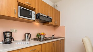 A kitchen with wooden cabinets, a microwave, a kettle, and a stove.