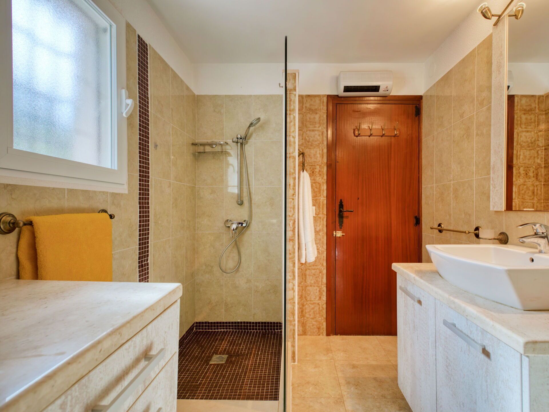Un baño con ducha, lavamanos y puerta de madera.