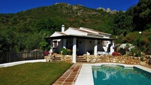 Una villa con piscina, escalones de piedra y vistas a un paisaje montañoso.