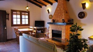 Una sala de estar acogedora con chimenea, televisor y comedor.