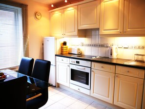 A kitchen with white cabinets, a black countertop, a built-in oven, and a clock on the wall.
