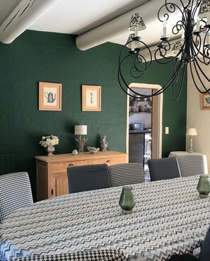 Un comedor con mantel estampado, una araña y cuadros en la pared.
