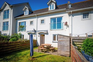 A two-story house with a patio, a wooden fence, and a satellite dish. - Modern well equipped townhouse, 2 min walk from Crooklets Beach (Bude)