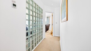 A hallway with a glass block wall, a framed picture, and a digital thermostat. - Modern well equipped townhouse, 3 min walk from Crooklets Beach, Bude (Bude)