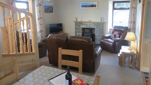 Una sala de estar con chimenea, sofás de cuero, un televisor y un comedor con mesa y sillas.