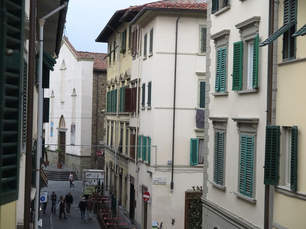 A narrow street with buildings featuring green shutters and a stop sign.