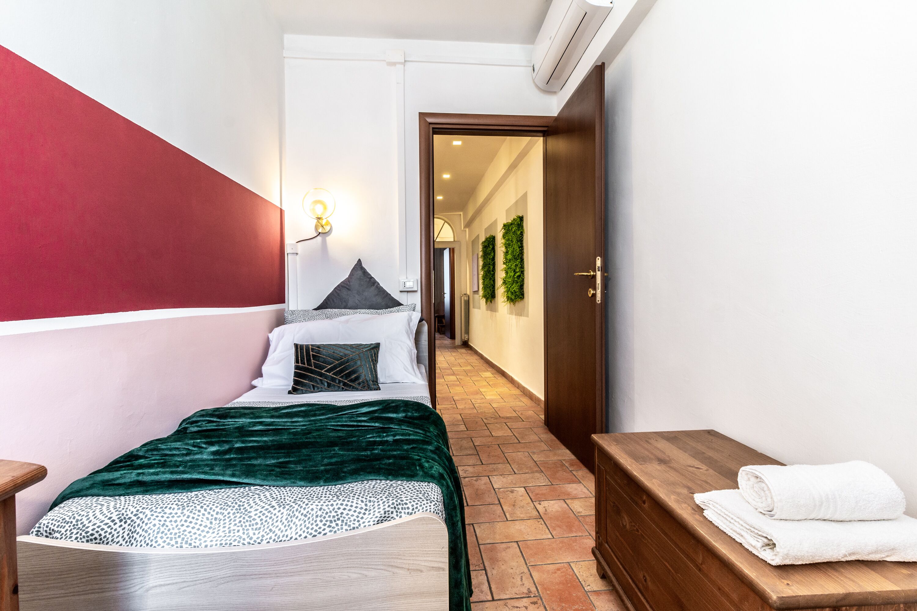 A modern hotel room with a bed, a wooden bench, and a towel on a bench.