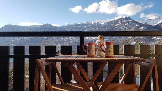 A wooden table with two mugs on a balcony overlooking a mountainous landscape. - Magnificent view ! Vallouise, Parc des Ecrins, Puy st Vincent, Pelvoux Hautes Alpes (Vallouise)