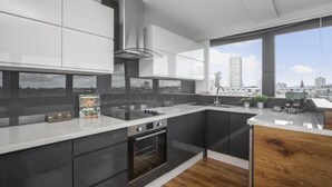 Una cucina moderna con un'isola grande, forno integrato e vista sulla città attraverso ampie finestre.