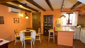 Un comedor con una mesa redonda y sillas, una isla de cocina con fregadero, y una puerta que da a otra habitación.