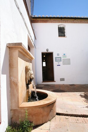 Ein Innenhof mit einem Brunnen, ein weißes Gebäude mit einer Tür und einem Fenster.