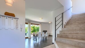 Interior moderno com escada, sala de jantar e vista para o verde lá fora.