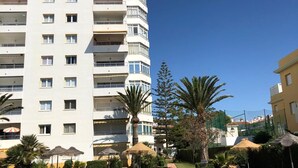 Ein modernes Hotel mit Swimmingpool, umgeben von Palmen und blauem Himmel.