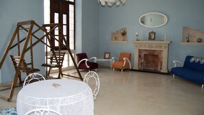 A room with a white round table, a swing set, a fireplace, and a blue sofa. - Hostal Sagrada Familia (Matanzas)